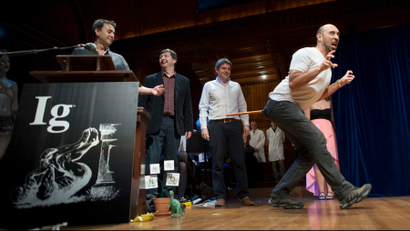 Bruno Grossi (R), walks like a dinosaur as he and his team accept the Ig Nobel Prize in Biology for observing that when you attach a weighted stick to the rear end of a chicken, it then walks in a manner similar to that in which dinosaurs.