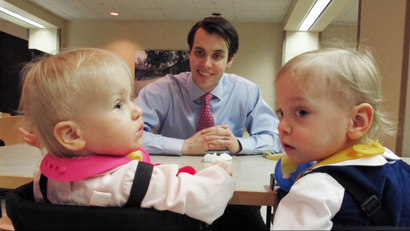 Man looks expectantly at twin babies at table