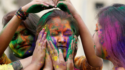 A college student reacts as others apply coloured powder on her face during Holi, the Festival of Colours, celebrations in Agartala