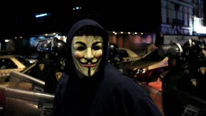 A protester wearing a Guy Fawkes mask walks past riot police during a demonstration by supporters of the Anonymous movement as part of the global "Million Mask March" protests in Mexico City November 5, 2013.