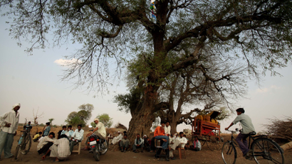 People sit under a tree outside the polling centre in Dorli village south-west of Nagpur city
