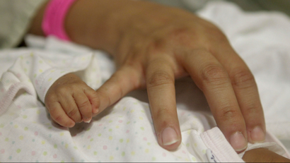 Baby hand holding mother's pinky finger.