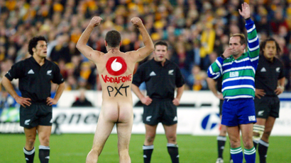 A streaker painted with an advertisment for international phone company Vodafone interrupts the Tri-Nations rugby union test between the New Zealand All Blacks and the Australian Wallabies in Sydney August 3, 2002. Vodafone apologised August 5, 2002, for two streakers which it unwittingly sanctioned to run into the middle of the rugby match wearing nothing but the phone company's logo.
