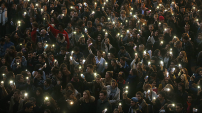 People light their mobile phones during a vigil.