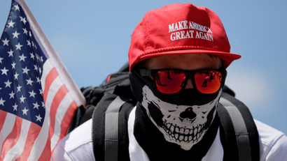 A masked demonstrator in a Donald Trump "Make America Great Again" hat listens to speeches as self proclaimed "White Nationalists", white supremacists and "Alt-Right" activists gather for what they called a "Freedom of Speech" rally at the Lincoln Memorial