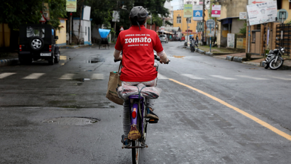 A delivery worker of Zomato rides her bicycle along a road in Kolkata
