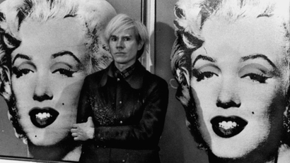 America's pop art painter and filmmaker, Andy Warhol, stands in front of his double portrait of the late Hollywood film star, Marilyn Monroe, at The Tate Gallery in London, February 15, 1971, at a press preview of his exhibition.