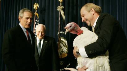 U.S. President George W. Bush (L) and Vice President Dick Cheney (2nd L) look on as turkey farmer Jim Trites introduces the national Thanksgiving Turkey, named Marshmallow, during a ceremony in the Eisenhower executive office building near the White House in Washington, November 22, 2005.