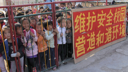 Children wait behind fence for their parents after school at a kindergarten in Tangying County