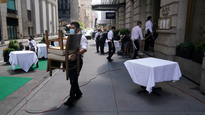 A waiter sets up tables in front of a restaurant in New York City.