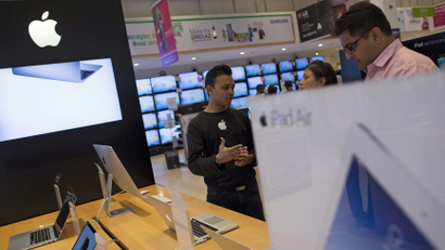An Apple salesperson speaks to customers at an electronics store in Mumbai, India,