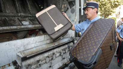 A French customs officer throws counterfeit leather goods into a garbage truck, Monday Sept. 28, 2009 in Cannes, southern France. The items were seized this summer in freight from China at Nice airport, and during regular controls at the French-Italian border. The goods are to be destroyed publicly Monday, as part of a campaign to educate the public about counterfeit goods.