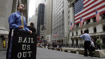 Man holds "bail us out" sign outside Wall Street during financial crisis