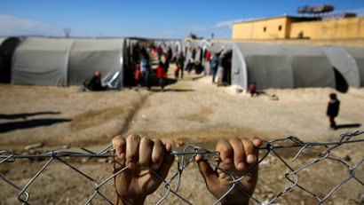 hands of a refugee boy grabbing the fence of a refugee camp in Turkey