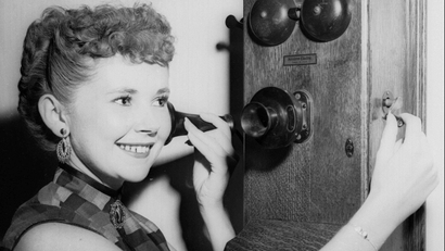Dolores Cady cranks the handle of an old fashioned telephone.
