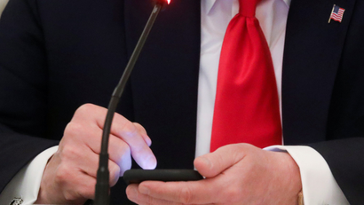 A close-up photograph of Donald Trump using a cellphone.