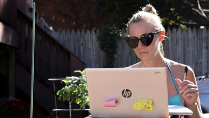 woman working outside with laptop wearing heart-shaped sunglasses
