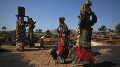 Girls carry bricks to be baked in a kiln at a brickyard on the outskirts of Karad in Satara district