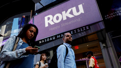 People pass the Roku logo in New York City