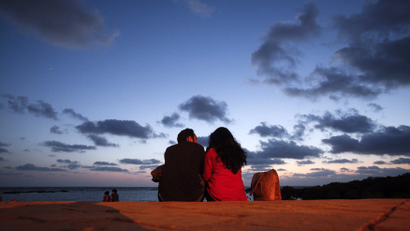 A couple sits along the seafront promenade at dusk in Mumbai's suburbs