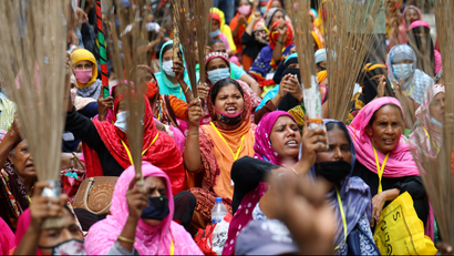 Garment workers shout slogans while holding brooms during a protest demanding their due wages in Dhaka, Bangladesh