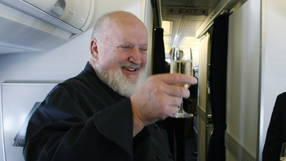 Renowned chef Michel Richard toasts with a glass of champagne as OpenSkies cabin crew Sabine Pena looks on aboard one of Openskies' Boeing 757-200 jets