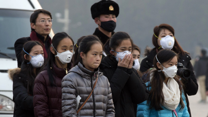 Young tourists wear masks as they stand near a Chinese Paramilitary policeman in Tiananmen Square in Beijing, China, Saturday, Dec. 19, 2015. Smog built up in the Chinese capital as the second red alert of the month went into effect, forcing many cars off the roads and restricting factory production. (AP Photo/Ng Han Guan)