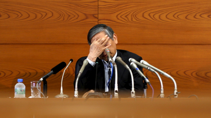 Bank of Japan (BOJ) Governor Haruhiko Kuroda touches his face during a news conference at the BOJ headquarters in Tokyo, July 15, 2015. The Bank of Japan trimmed its economic growth forecast on Wednesday but held off on offering fresh stimulus, convinced that an expected pick up in consumption will help accelerate inflation toward its 2 percent target.