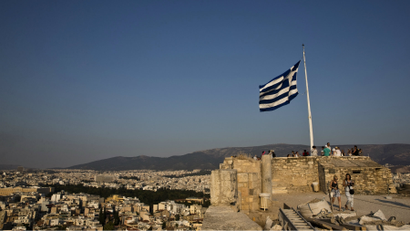 A Greek flag flutters in the wind as tourists visit the archaeological site of the Acropolis hill in Athens.