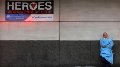 A doctor stands outside an emergency entrance under a sign reading "HEROES"
