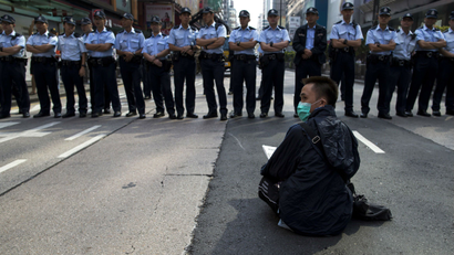 A pro-democracy protester sits in front of a line of policemen on a blocked road at Mongkok shopping district in Hong Kong.