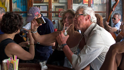 FILE - This Sunday, March 22, 2015 file photo shows tourists taking pictures of themselves as they drink a cocktail at the Bodeguita del Medio Bar frequented by the late American novelist Ernest Hemingway, in Old Havana, Cuba. Tourists trying to dine at high-end private restaurants are often struggling to find an empty table these days, and it's practically impossible to get a room at Havana's best hotels.