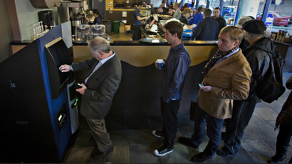 Customers line-up to use the world's first ever permanent bitcoin ATM unveiled at a coffee shop in Vancouver, Canada.