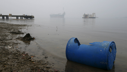 An idle oil exploration vessel (L) is shrouded by haze in the Johor River in Malaysia's southern state of Johor..