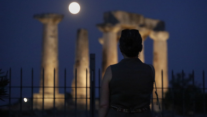 A woman watches the super moon rising in the sky, in front of the Apollo's temple at ancient Corinth, about 80 kilometers (50 miles) southwest of Athens, on Sunday, Aug. 10, 2014. The phenomenon, which scientists call a "perigee moon," occurs when the moon is near the horizon and appears larger and brighter than other full moons. (AP Photo/Petros Giannakouris)