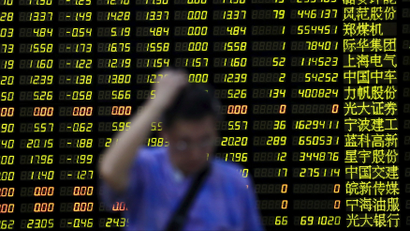 An investor stands in front of an electronic board showing stock information at a brokerage house in Shanghai, China.