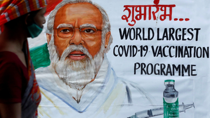A woman walks past a painting of Indian Prime Minister Narendra Modi a day before the inauguration of the COVID-19 vaccination drive on a street in Mumbai