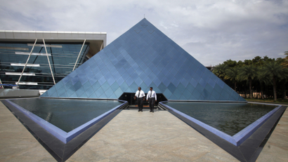 Employees walk in front of a pyramid-shaped building at the Infosys campus in the Electronic City area of Bangalore