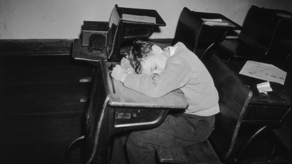A young boy asleep in class
