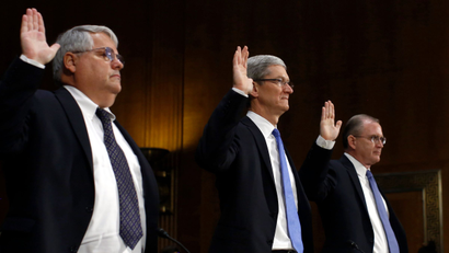 Apple CEO Tim Cook (C) , CFO Peter Oppenheimer (L) and Apple Head of tax operations Philip Bullock are sworn in to testify at a Senate homeland security and governmental affairs investigations subcommittee hearing on offshore profit shifting and the U.S. tax code, on Capitol Hill in Washington, May 21, 2013. Apple Inc came under fire on Tuesday at a Senate hearing over an investigation that alleged the U.S. high technology icon has kept billions of dollars in profits in Irish subsidiaries and paid little or no taxes to any government.