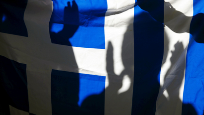 The silhouette of a woman applauding is seen on a Greece flag during a pro-Greece protest in front of the European Union office in Barcelona, Spain, June 29, 2015.