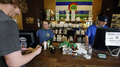 A customer pays cash for retail marijuana at 3D Cannabis Center, in Denver, Thursday, May 8, 2014. Frustrated by the cash-heavy aspect of its new marijuana industry, Colorado is trying a long-shot bid to create a financial system devoted to the pot business. But according to many industry and regulatory officials, Colorado's plan to move the weed industry away from cash to easily auditable banking accounts won't work. (AP Photo/Brennan Linsley)