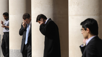 City workers make phone calls outside the London Stock Exchange in Paternoster Square in the City of London