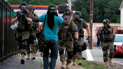 FILE - In this Aug. 11, 2014 file photo, police wearing riot gear walk toward a man with his hands raised in Ferguson, Mo. U.S. Sen. Claire McCaskill holds a teleconference on Thursday, May 7, 2015, to announce she will introduce a bill, to reform federal programs that provide military equipment to police, responding to allegations that local law enforcement overreached by using armored vehicles and high-caliber weapons during Ferguson protests. McCaskill introduced the Protecting Communities and Police Act on Thursday, and U.S. Rep. William Lacy Clay plans to propose a companion version next week.