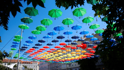 Two women walk under colourful umbrellas decorating Dorner Platz in Vienna