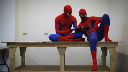 Peter Norbot and Kris Hamilton (L), dressed up as fictional comic book superhero Spider-Man, look through a magazine as they wait for their turn to audition to be a part of a promotional campaign for the upcoming release of the new movie "The Amazing Spider-Man 2" in Chicago March 19, 2014.