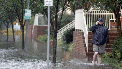 sea level rise storm surge flooding climate change global warming virginia A resident talks on his cell as he walks through a flooded street in Norfolk, Va., Friday, Nov. 13, 2009. The area has been hit by remnants of tropical storm Ida. (AP Photo/Steve Helber
