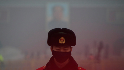 A paramilitary police officer wearing a mask stands guard in front of a portrait of the late Chairman Mao Zedong during smog at Tiananmen Square after a red alert was issued for heavy air pollution in Beijing, China, December 20, 2016. REUTERS/Jason Lee - RTX2VRON