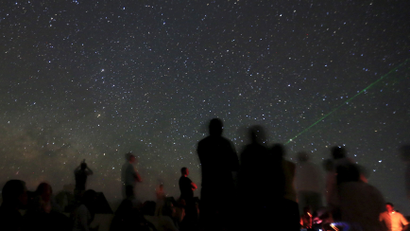 Campers look up at stars in the night sky in the White Desert north of the Farafra Oasis southwest of Cairo