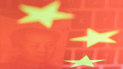 A Chinese yuan banknote and a computer keyboard reflected on a Chinese flag.